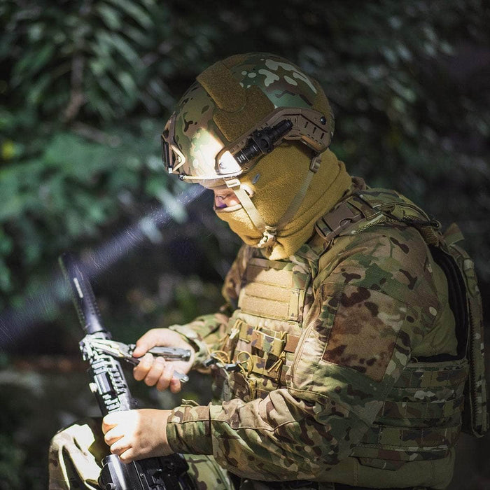 Soldier in camouflage gear inspecting a rifle, wearing a helmet with a mounted Weltool T1 Pro TAC mini tactical flashlight, surrounded by lush greenery.