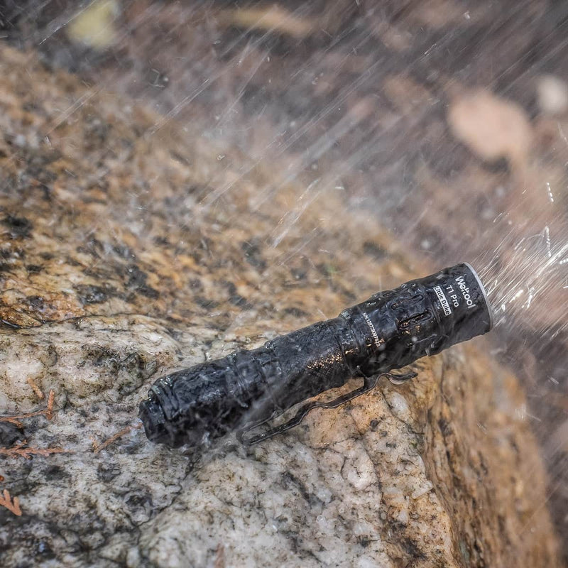 The Weltool T1 Pro V3 rests on a wet rock outdoors, water spraying over it, showcasing its strong water-resistant capability.