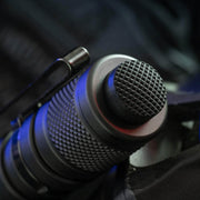 Close-up of the Weltool T15's textured black LED tactical flashlight tail switch with a metal clip, illuminated by blue and red light.