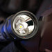 Close-up view of the lens and LED bulb inside a black Weltool T15 LED tactical flashlight, highlighting the reflective interior surface.
