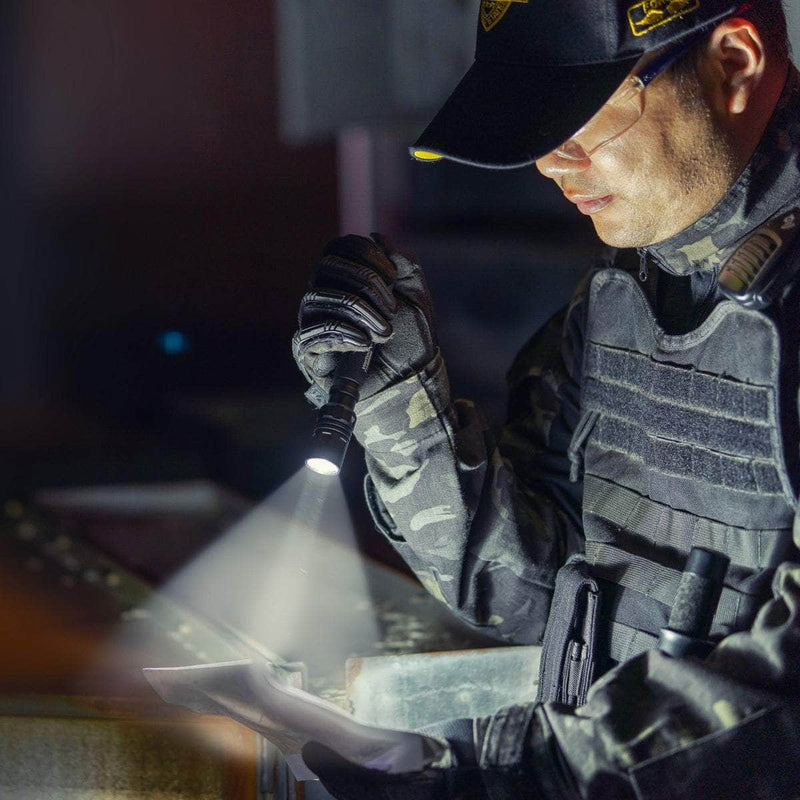 A person in tactical gear and a cap examines papers with the Weltool T15 rechargeable flashlight in a dimly lit environment.