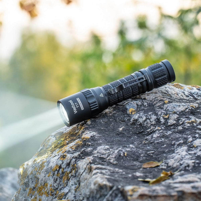 A durable Weltool T17 is sitting on top of a rock, emitting a powerful beam in high mode.