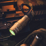 A Weltool W15 “Flying Divinity” LEP Tactical Flashlight with an attached lanyard rests on a rifle, surrounded by military gear and fabric in the background.