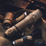 A tan Weltool W15 “Flying Divinity” LEP tactical flashlight sits on a mesh bag, surrounded by flashlight parts and outdoor equipment.