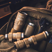 Tan-colored metal components and tools for the Weltool W15 “Flying Divinity” LEP Tactical Flashlight are displayed on a brown fabric bag, showing detailed threads and distinctive branded logos on each item.