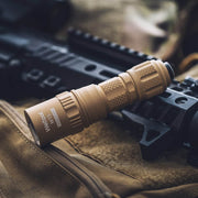 A tan Weltool W15 “Flying Divinity” LEP Tactical Flashlight rests on a black firearm atop a tan fabric surface.