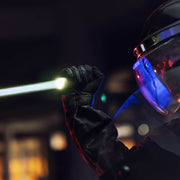 A person in riot gear and a helmet holds up a baton with a bright light at the end, illuminated by the Weltool W15 “Flying Divinity” LEP Tactical Flashlight in a dark setting.