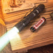 A Weltool W2 flashlight, the mini LEP tactical flashlight capable of illuminating up to 800 meters, is placed on a wooden table alongside a battery.