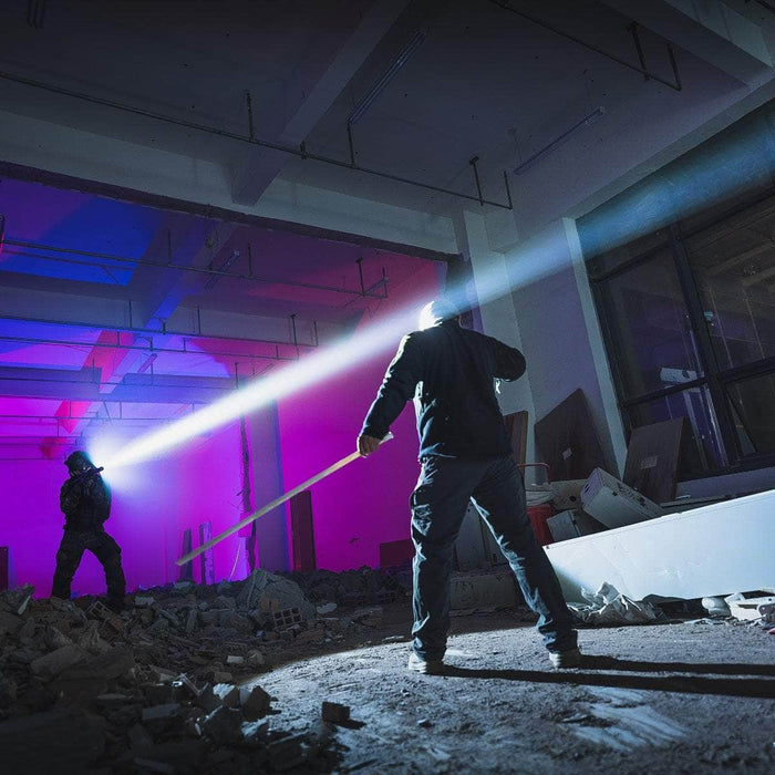 In a debris-filled room with colorful lights, one person shines a Weltool W35S compact tactical light while the other holds a long pole.