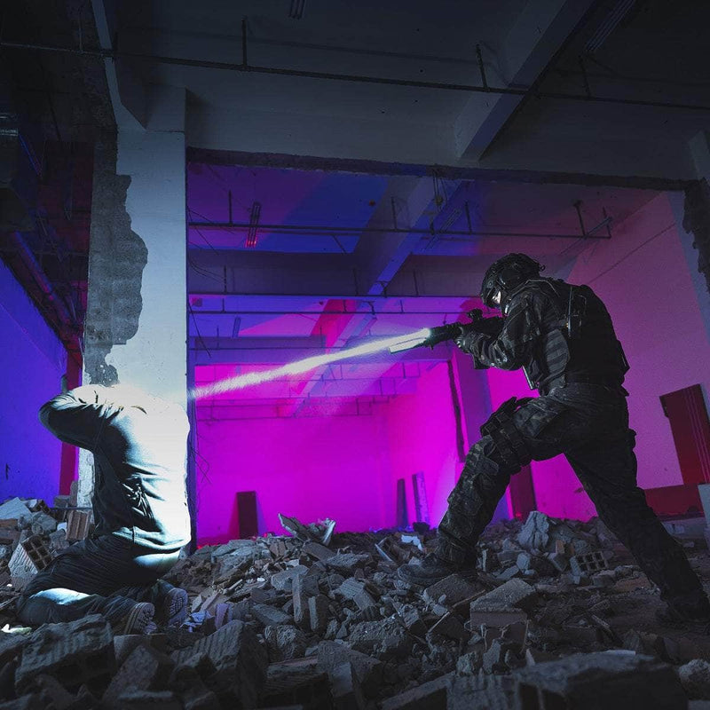 A person in tactical gear aims the Weltool W35S compact light at a kneeling figure amid rubble in a dimly lit building illuminated by purple and blue lights.