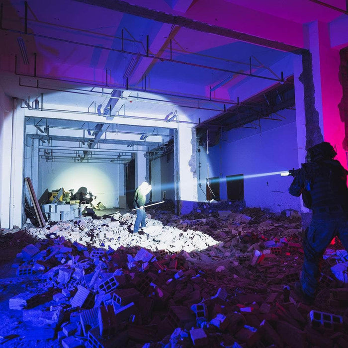 People with flashlights, including the compact tactical Weltool W35S, search through rubble in a dimly lit, partially demolished building. Blue and purple lighting highlight the scene.