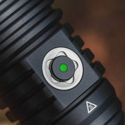 Close-up of the Weltool W5R Pro LEP flashlight's black power button with a green indicator light, metallic ring, and textured grip, featuring waterproof USB-C charging for reliable performance.