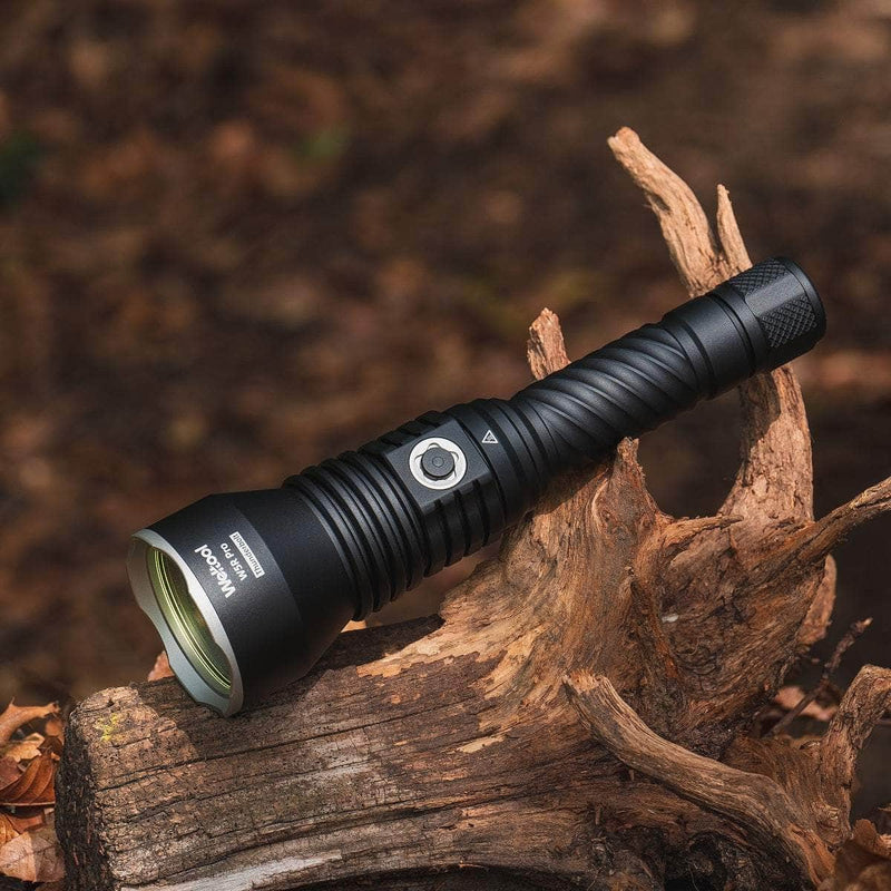 A Weltool W5R Pro LEP rechargeable flashlight sits on weathered wood among dry leaves and bark—ideal for anyone needing a powerful, waterproof USB-C throwing flashlight.