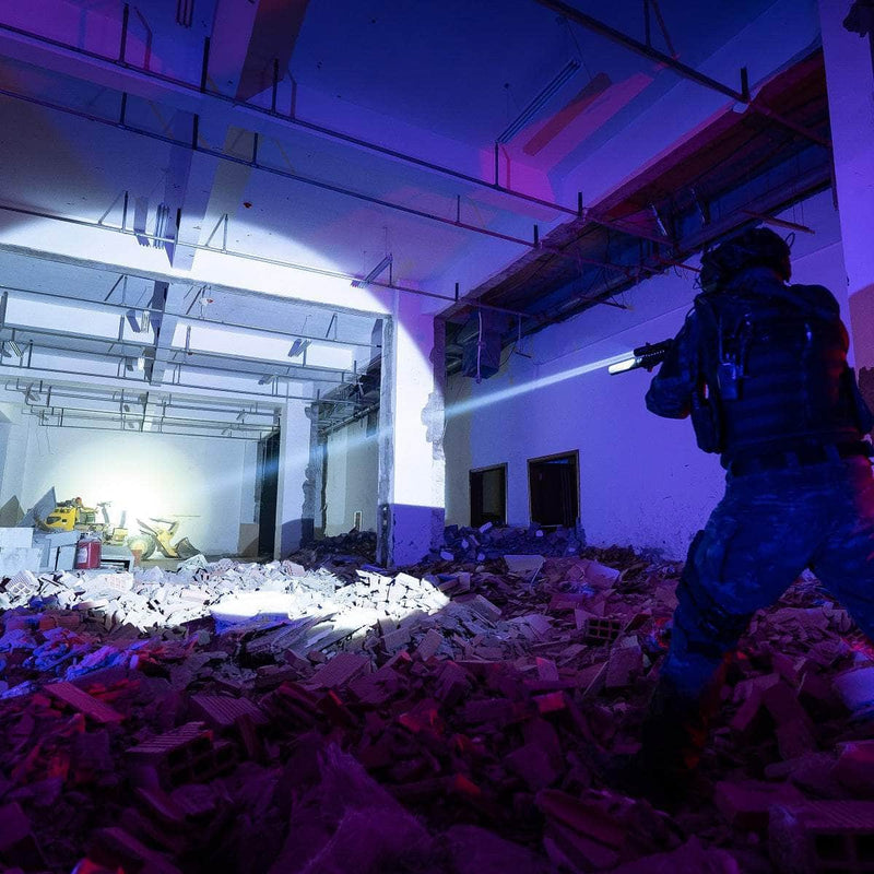 Clad in tactical gear and carrying a rifle, a person uses the Weltool W65S high candela flashlight to navigate a debris-filled, partially destroyed building at night.