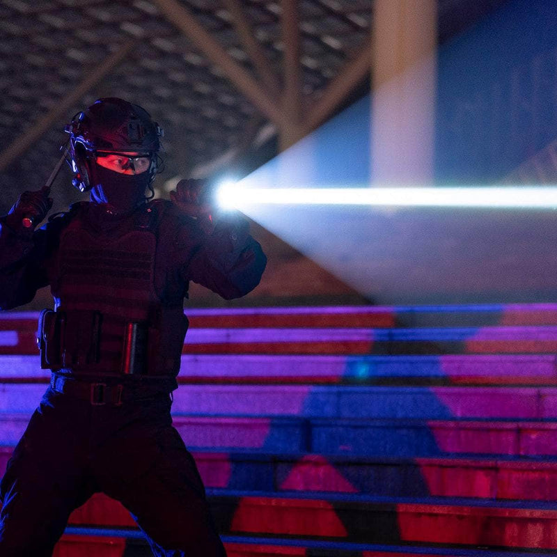 A person in tactical gear and helmet stands on steps at night, shining a Weltool W7 LEP tactical flashlight (700 lumens), with blue and red lights illuminating the scene.