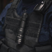 A person wearing a tactical vest with a Weltool W7 long-range LEP tactical flashlight (700 lumens) clipped to the front and a radio attached to the shoulder.