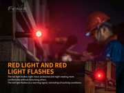A worker wearing a hard hat uses the versatile Fenix HM61R headlamp outdoors at night. Its dual light sources effectively illuminate the area, while an additional flashlight with a red light attached to a railing indicates active work conditions.