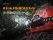 The Fenix HM61R, equipped with dual light sources, is depicted in a downpour. The accompanying text emphasizes its IP68 protection rating, highlighting that it is both dust-proof and water-resistant up to 2 meters for 30 minutes, making this versatile headlamp perfect for tough outdoor excursions.