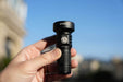 A person holding a Manker MC13 II - SBT90.2 flashlight in front of a city.