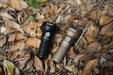 Two Manker MC13 II - SBT90.2 flashlights laying on the ground next to each other.