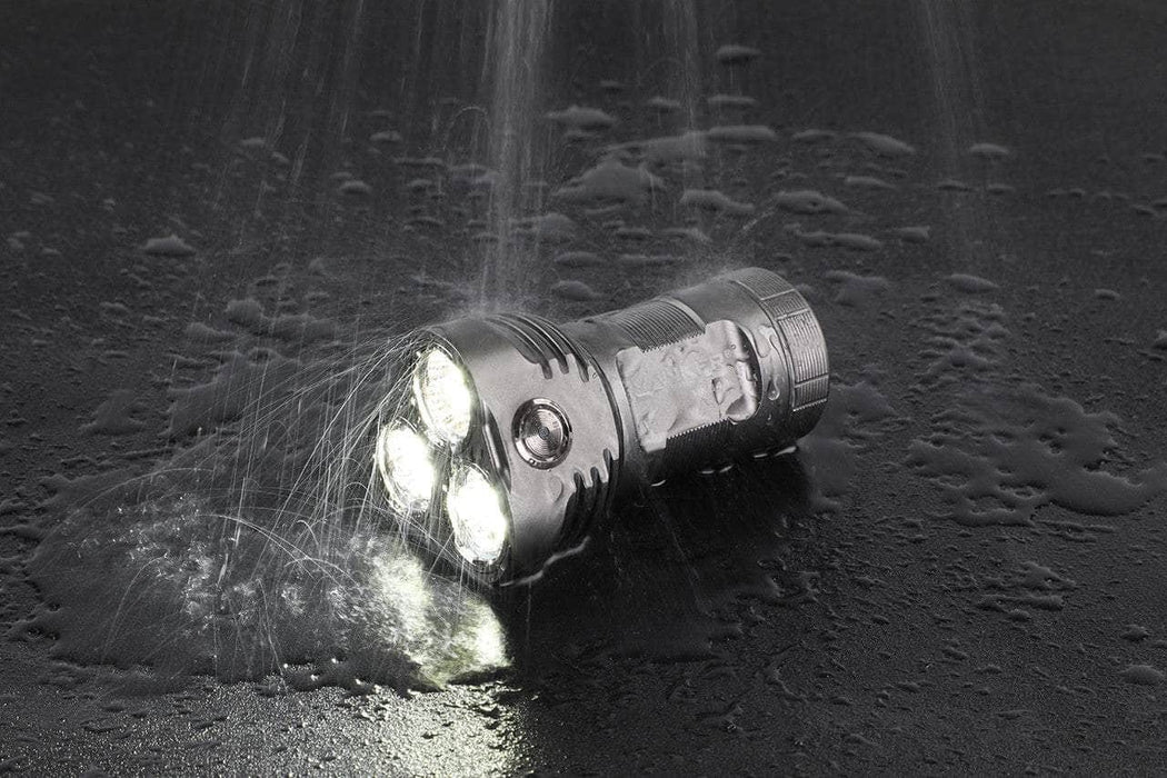 A Manker MK34 II flashlight with water splashing on it.