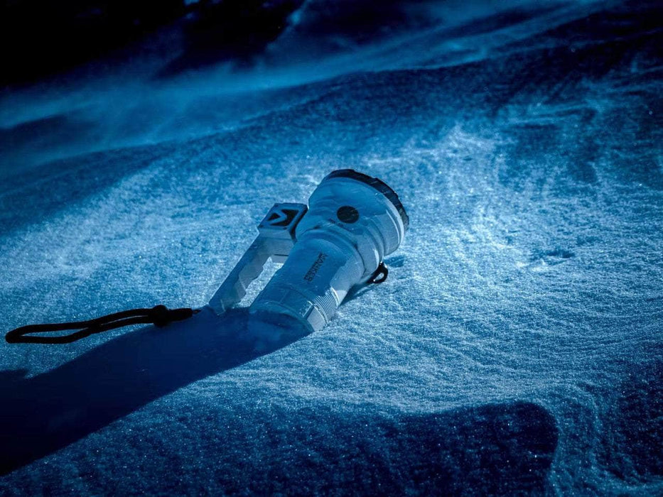 A Manker MK38 Satellite flashlight laying in the snow at night.