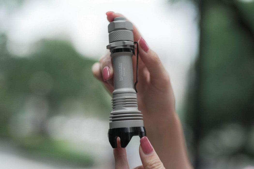 A person holding a Manker Striker - Aluminum flashlight in their hand.