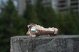 A Manker Striker - Copper flashlight sitting on top of a rock.