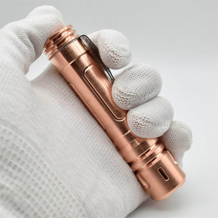 A hand holding a ReyLight LAN Copper flashlight.