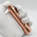 A hand holding a ReyLight LAN Copper flashlight.