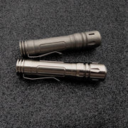 Two ReyLight LAN Titanium flashlights with durable clips rest parallel on a textured black surface, each casting illumination from their Nichia 219B LEDs.