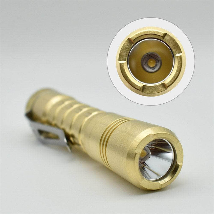 A ReyLight Pineapple Brass flashlight with a clip on it.