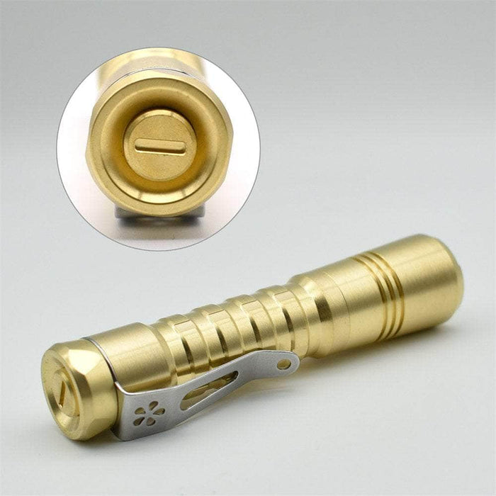 A ReyLight Pineapple Brass flashlight with a metal handle.