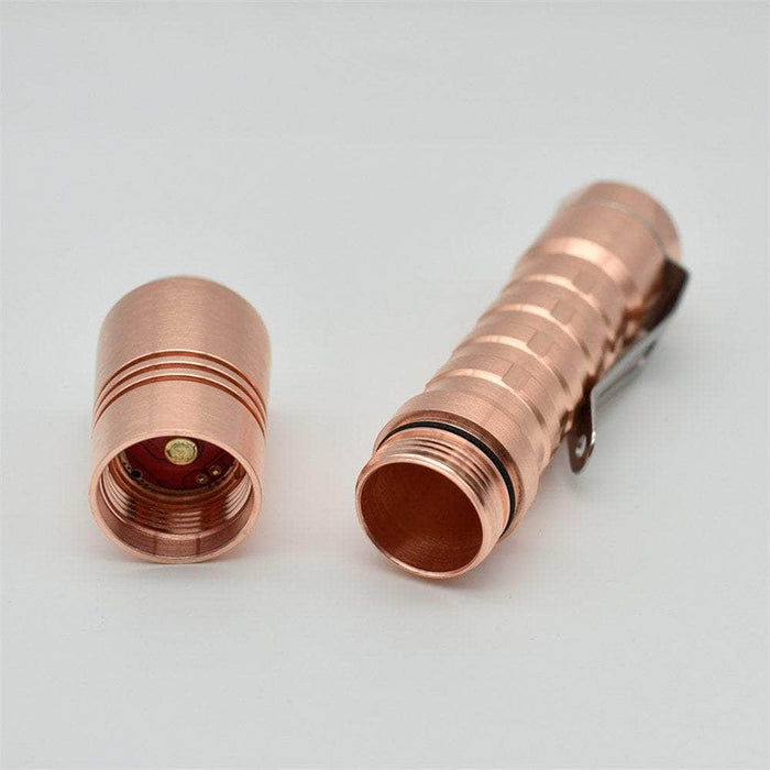 A pair of ReyLight Pineapple Copper flashlights on a white surface.